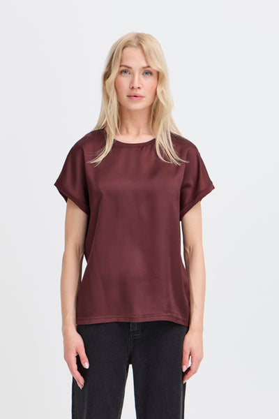 Woman wearing a maroon t-shirt and black pants on a white background
