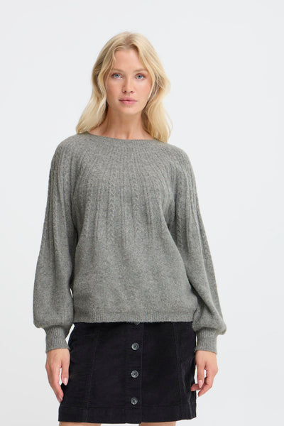 Woman wearing a gray sweater and black skirt on a white background