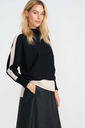 Woman wearing a black and beige sweater with a white background