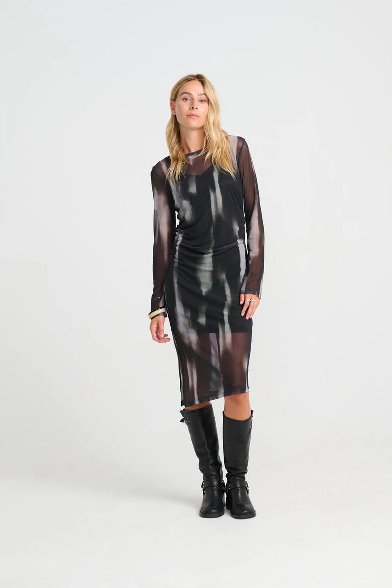 Woman wearing a costamani depp black brown mesh dress with long sleeves and black boots on a white background