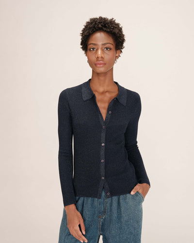 Woman wearing a dark blue lurex cardigan against a beige background