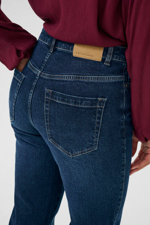 Person wearing blue jeans with a visible brand label on a white background