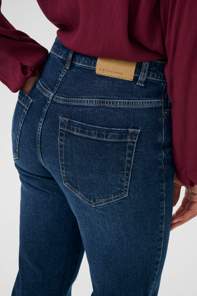 Person wearing blue jeans with a visible brand label on a white background