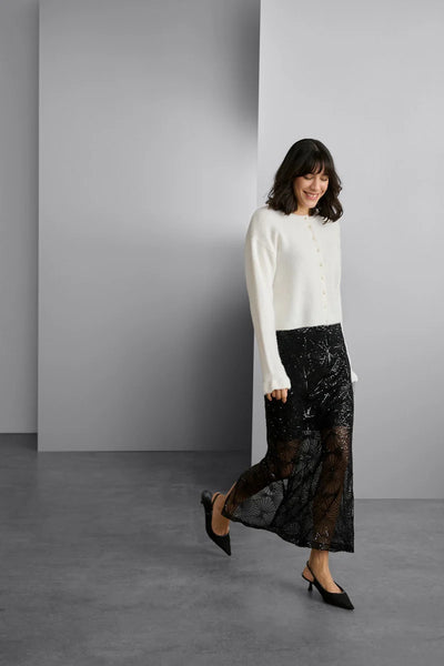 Woman wearing a white blouse and black lace skirt against a gray background