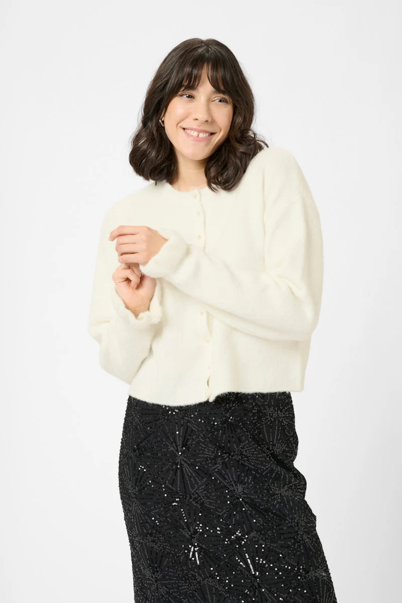 Woman wearing a white sweater and black sequin skirt on a white background