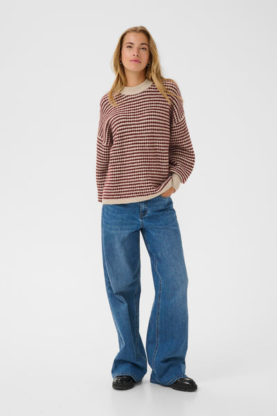 Woman wearing a kaffe ellery sweater and blue jeans on a white background