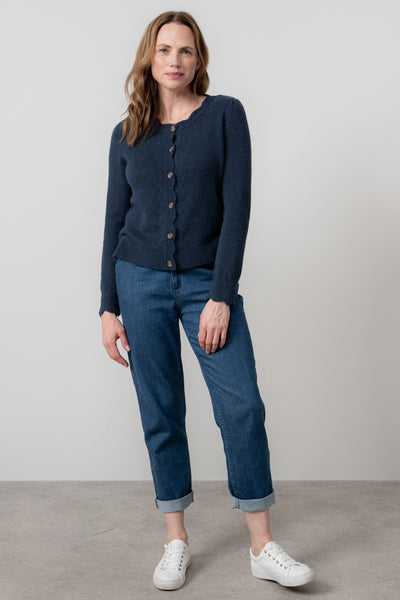 Woman wearing lily & me navy cardigan and blue jeans standing against a plain background