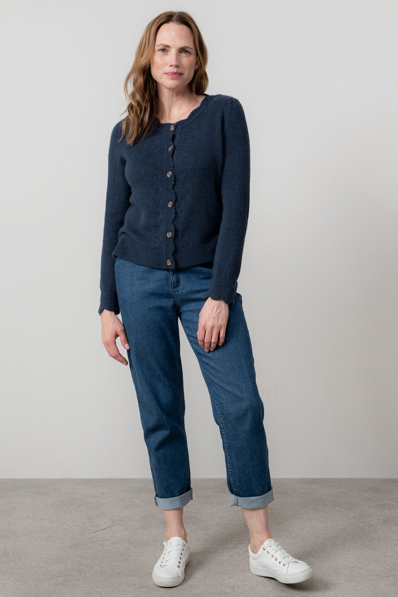 Woman wearing lily & me navy cardigan and blue jeans standing against a plain background