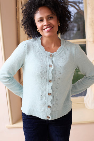 Woman wearing lily & me soft blue layla cardigan with a lace pattern, standing indoors.