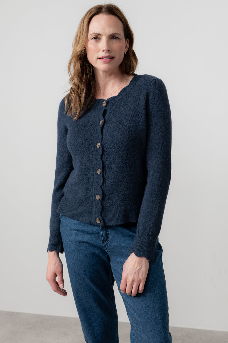 Woman wearing lily & me navy blue cardigan and jeans against a plain background