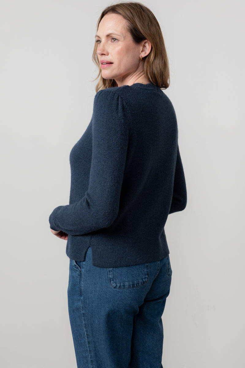 Woman wearing lily & Me navy sweater and jeans against a light gray background