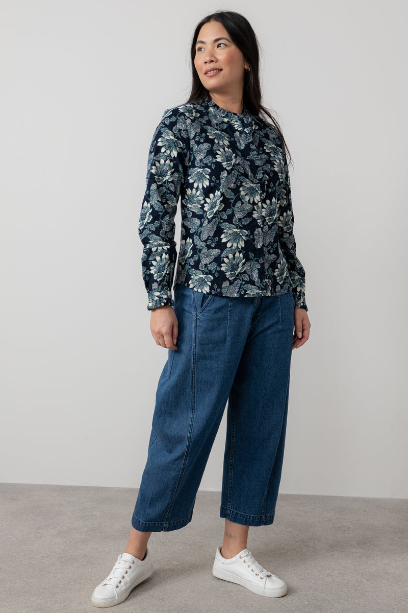 Woman wearing lily & me navy floral blouse and blue jeans against a plain background