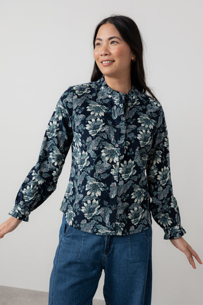 Woman wearing lily & me dark floral blouse and blue jeans against a plain background