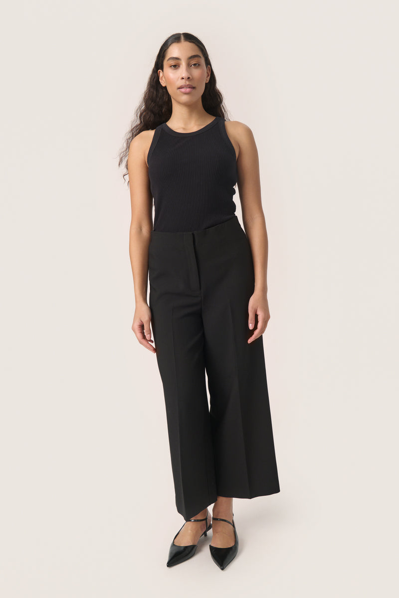 Woman wearing Soaked wide-leg pants with black sleeveless top on a white background