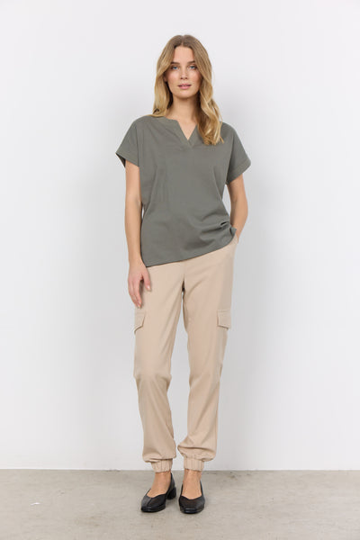 Front full view of Soyaconcept Short Sleeve sage green top with tailored v neck. Shown worn loose with beige trousers