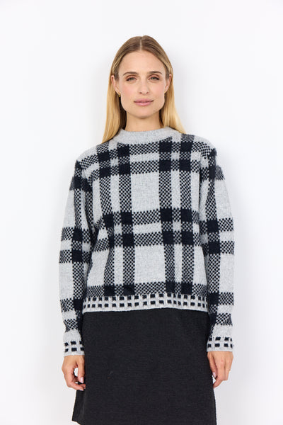 Woman wearing soyaconcept black and white checkered sweater against a white background