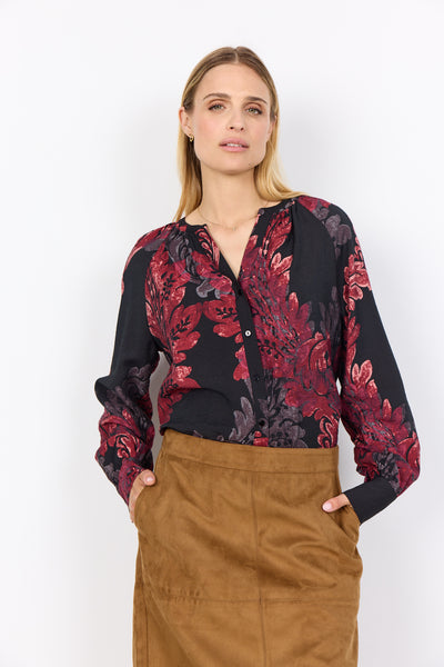 Woman wearing a black floral blouse with red and purple patterns on a white background