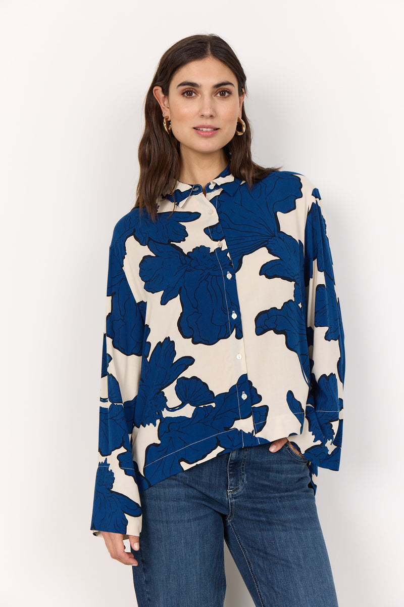 Woman wearing a blue and white floral blouse against a white background