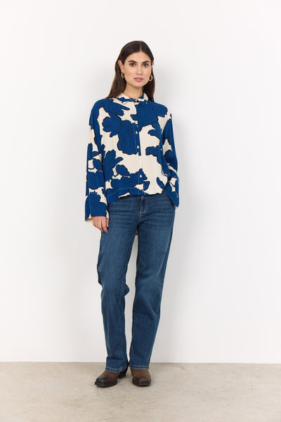 Woman wearing a blue and white floral shirt and jeans on a white background