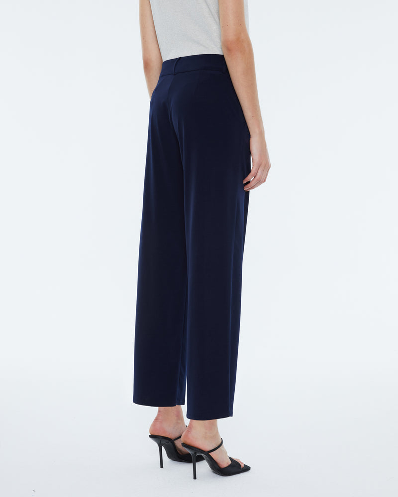 rear view showing model wearing ankle length silky trousers with high heels and white t shirt