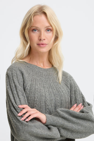 Woman wearing a gray sweater against a white background