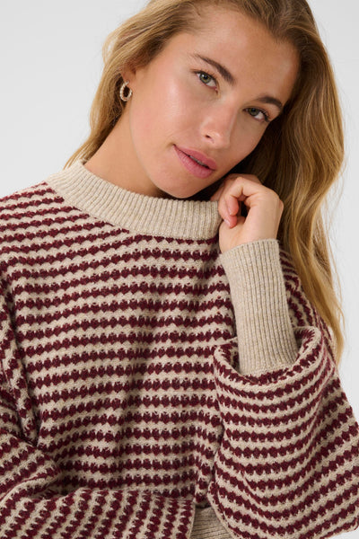 Woman wearing a kaffee ellery sweater against a white background