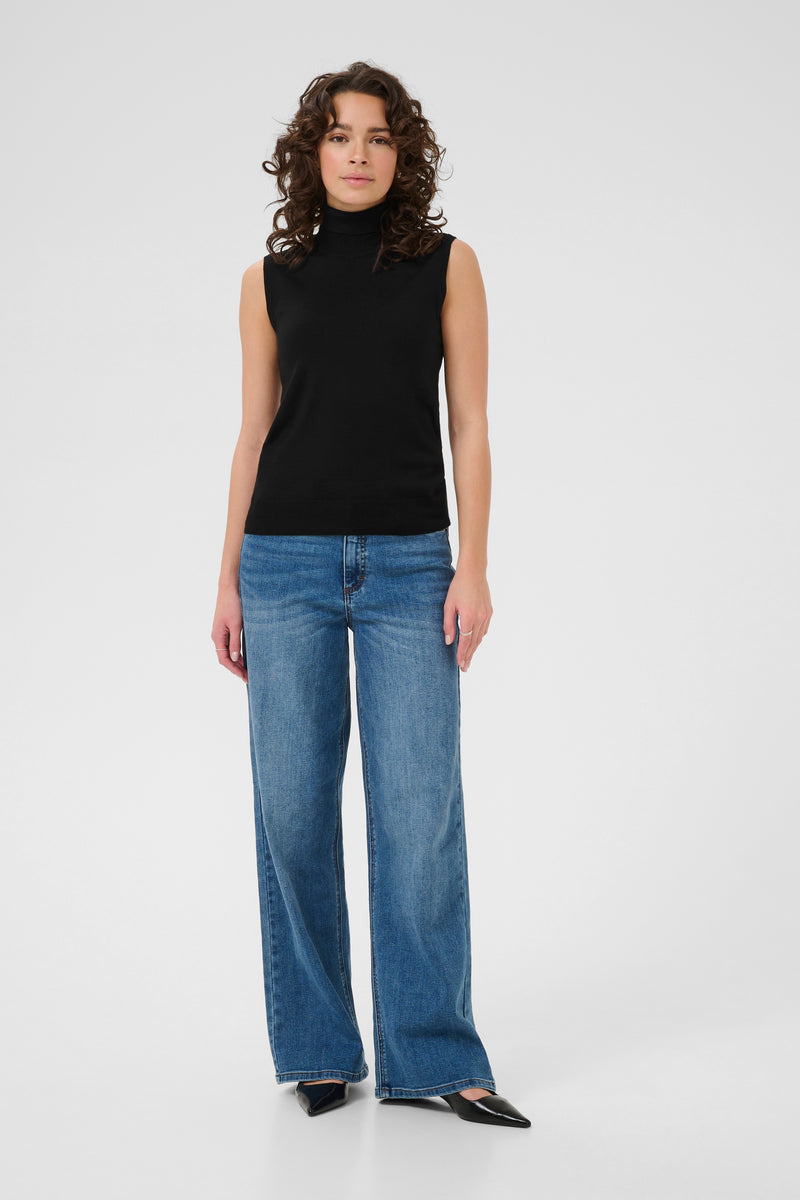Woman wearing kaffe black sleeveless top and blue jeans on a white background