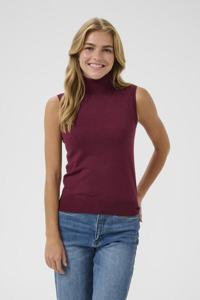 Woman wearing kaffe burgundy sleeveless top and blue jeans on a white background
