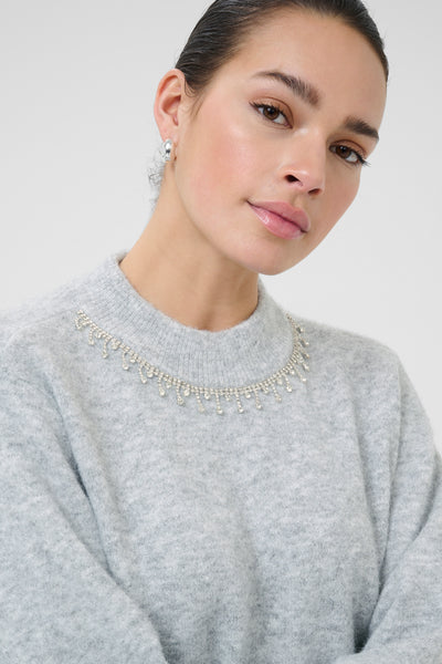 Woman wearing kaffe gray sweater with a decorative neckline 