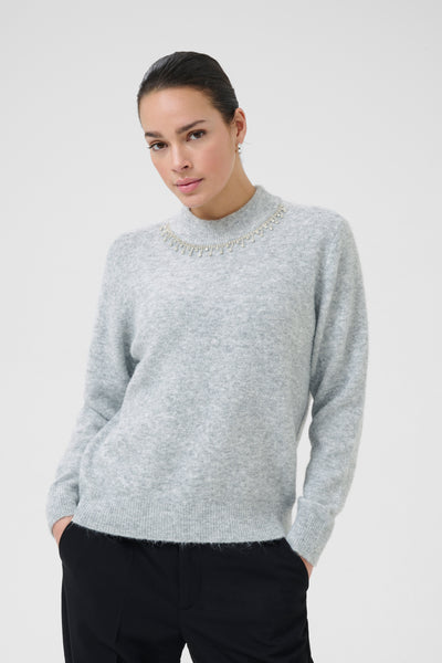 Woman wearing kaffe light gray sweater on a white background