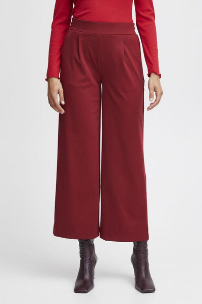 Red top and wide-leg Burgundy pants worn by a person on a white background